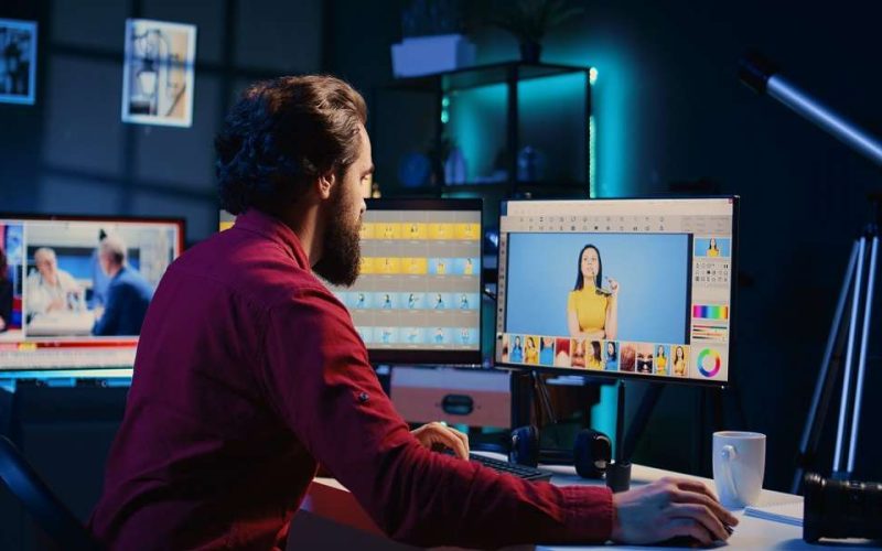 Photo editor color correcting photographs in creative studio using graphic tablet, jib down shot. Photographer selecting best pictures for editorial content using stylus on touchscreen device